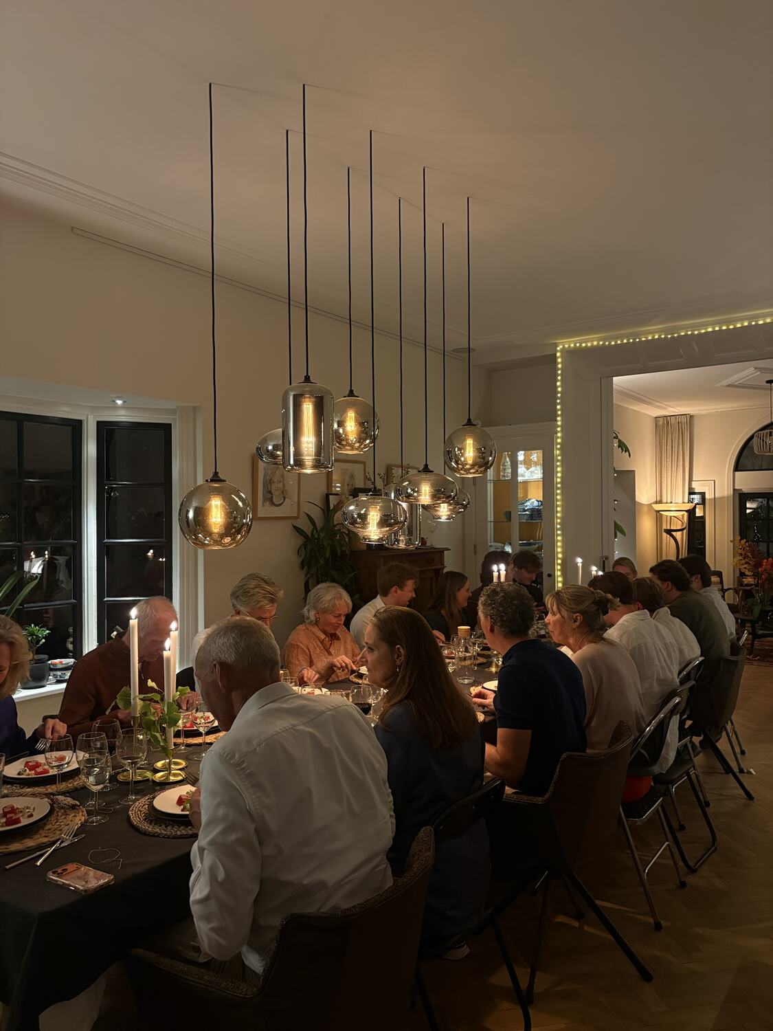 Gasten aan een lange tafel bij kaarslicht